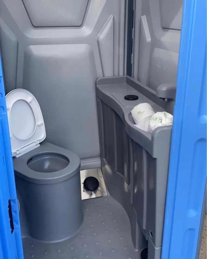 Deluxe porta potty interior with toilet, counter and toilet paper dispenser