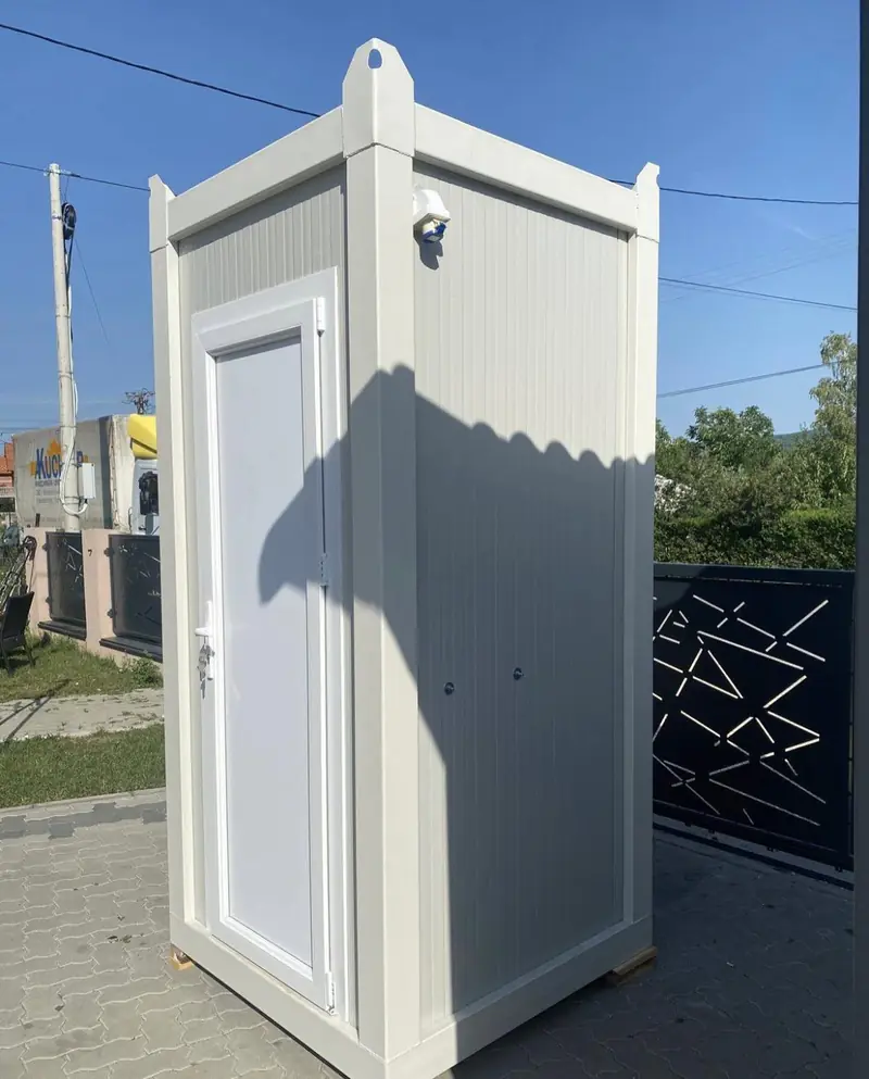 White single-stall flushing restroom cabin set on a driveway