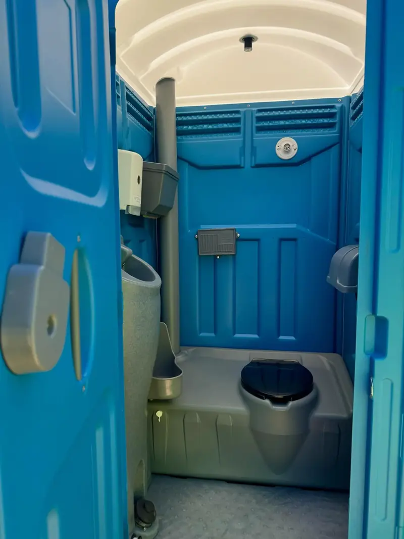 Wide porta potty interior with toilet, urinal and ventilation stack