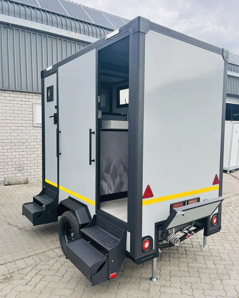 Rear view of a compact restroom trailer with steps and stabilizer jacks