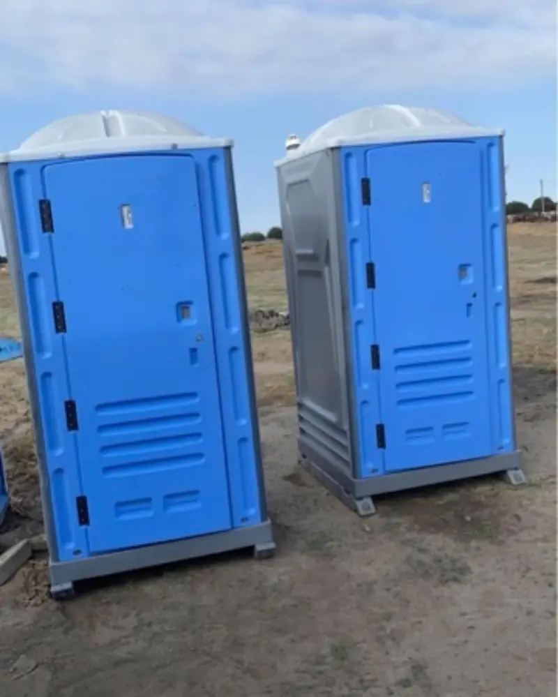 Blue standard porta potties delivered to an open dirt jobsite lot